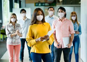 Group of people working at a creative office wearing facemasks stock photo
