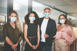 Shot of a diverse group of businesspeople standing together in the office and wearing face masks stock photo
