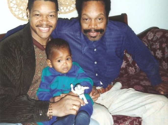 Photo of Demetrius Parker in 1996 holding his young son Vitthal, and seated next to his late father John H. Parker, Sr.