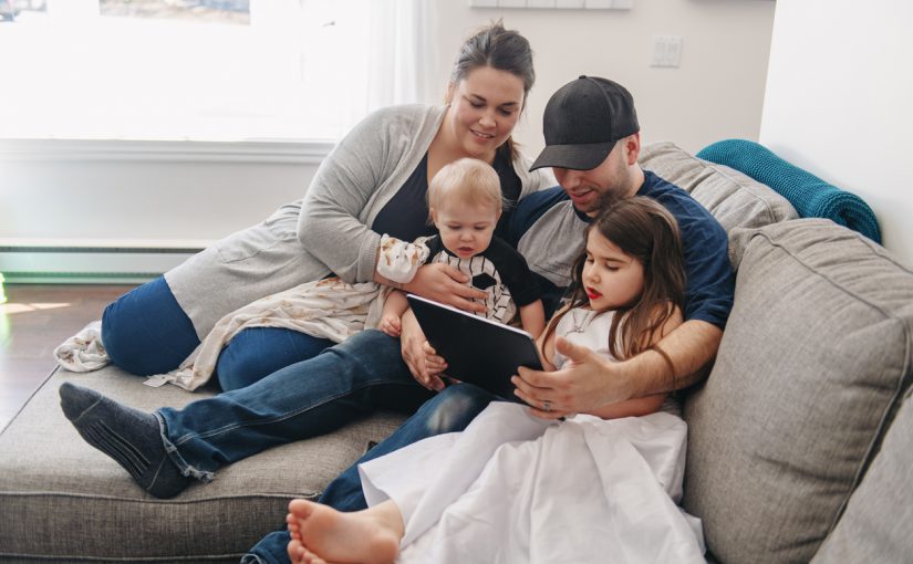 Millennial generation Family relaxing in living room. Father using a digital tablet with his son and his little austim girl