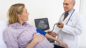 a doctor checking the blood pressure of a pregnant person