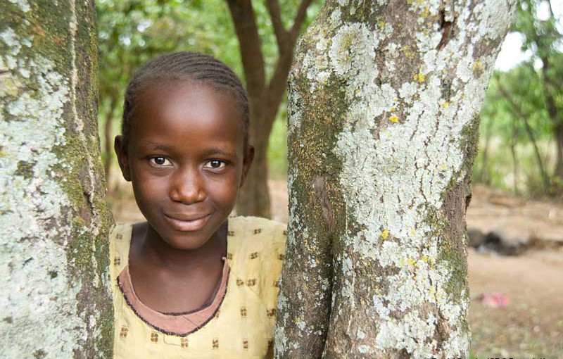 A girl leans against a tree in the village of Usoma, Kenya.