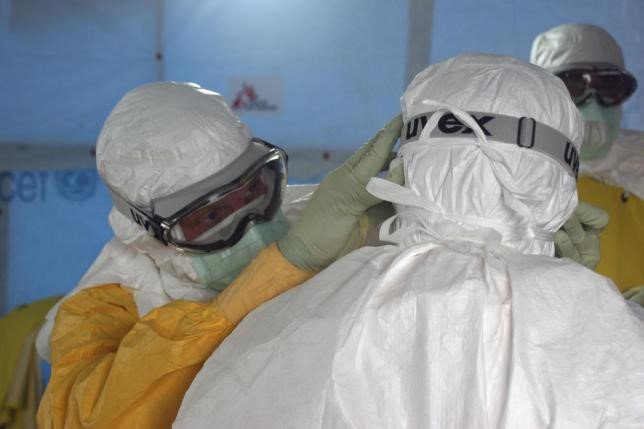 Dr. Joel Montgomery, dressed in personal protective equipment (PPE), adjusts a colleague's PPE before entering the Ebola treatment unit in Monrovia, Liberia.