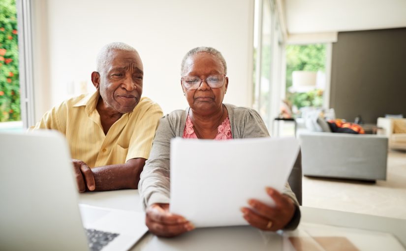 African American senior couple reading a document at home.