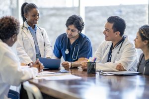 A small group of medical professionals at a table together discussing patient care.