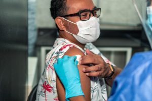 Hispanic or Latino man receiving vaccine at local clinic.