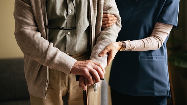 An individual is being assisted by another person, who is wearing a medical uniform.