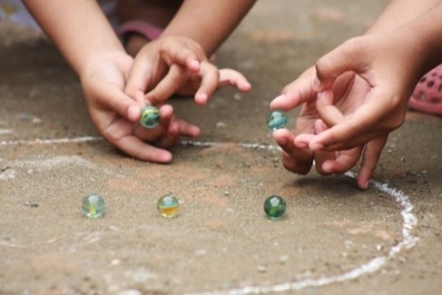 close up of hands playing a game of marbles