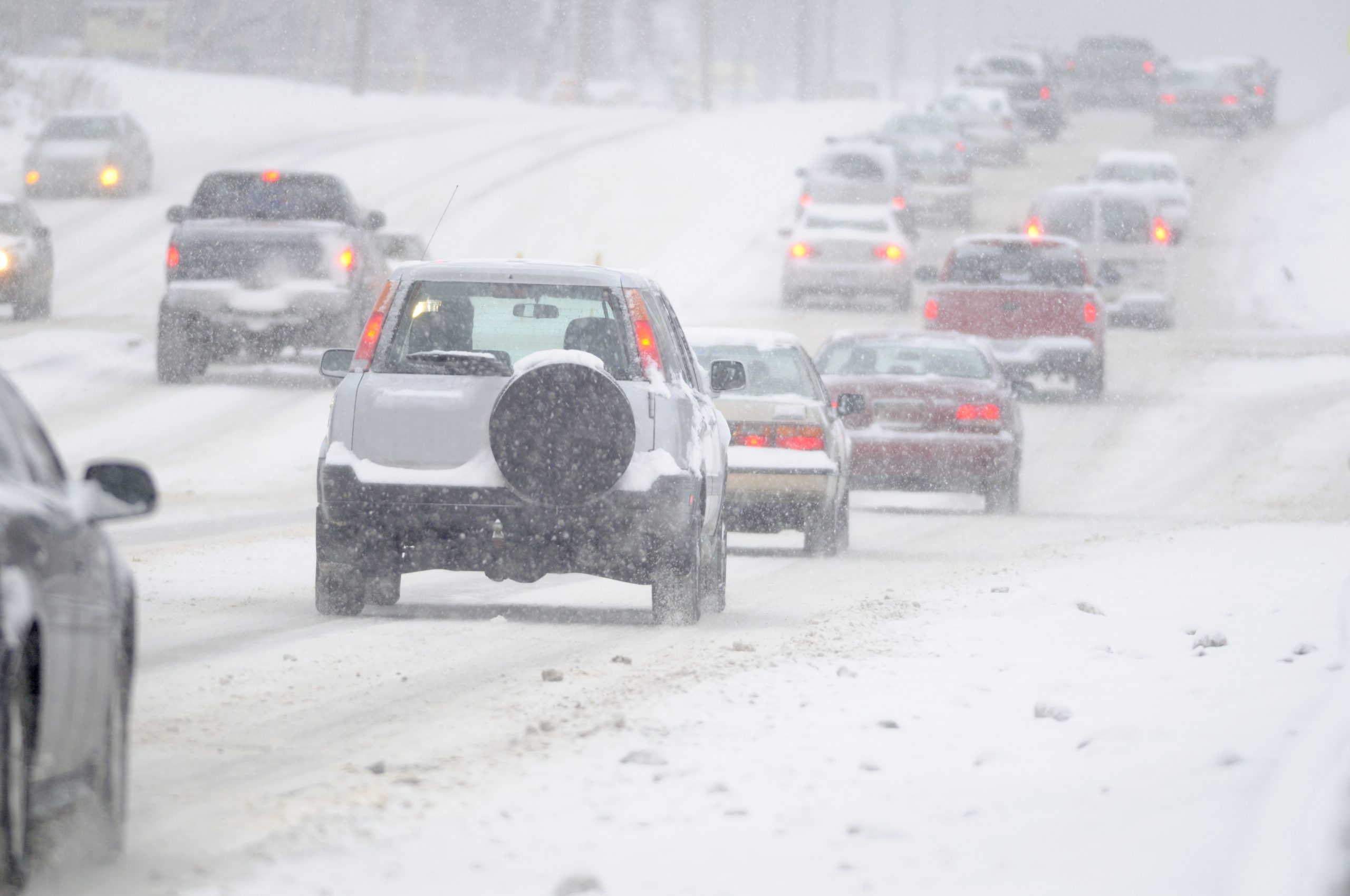 vehicles driving on snow covered road. 