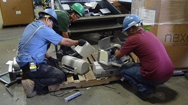 Recycling workers manually disassemble printers