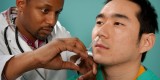 Male doctor administering flu mist on a male patient