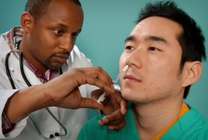 Male doctor administering flu mist on a male patient