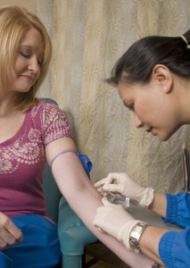 Woman receiving flu vaccination in her arm by a female nurse