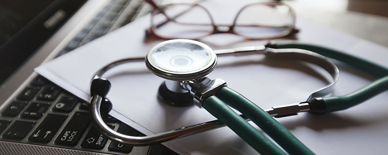 stethoscope on a piece of paper on top of a computer next to reading glasses