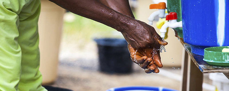 A person washing their hands at a water station in West Africa