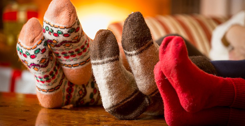 Closeup photo of family feet in wool socks at fireplace