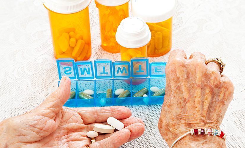 Closeup view of an eighty year old senior woman's hands as she sorts her prescription medicine.