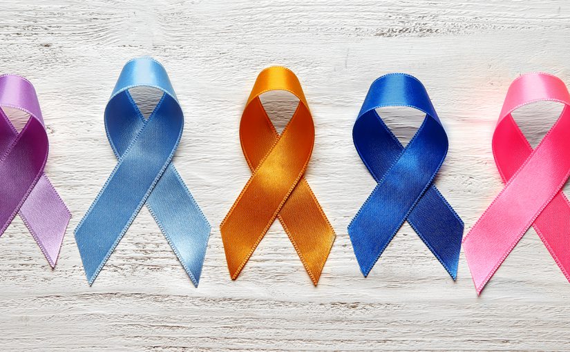 Different colorful ribbons on white wooden background. Cancer concept