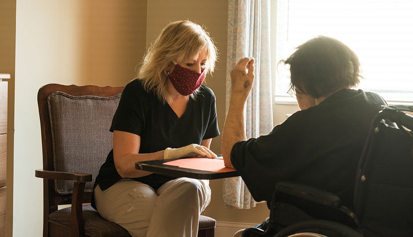 Two women having a conversation and wearing masks.