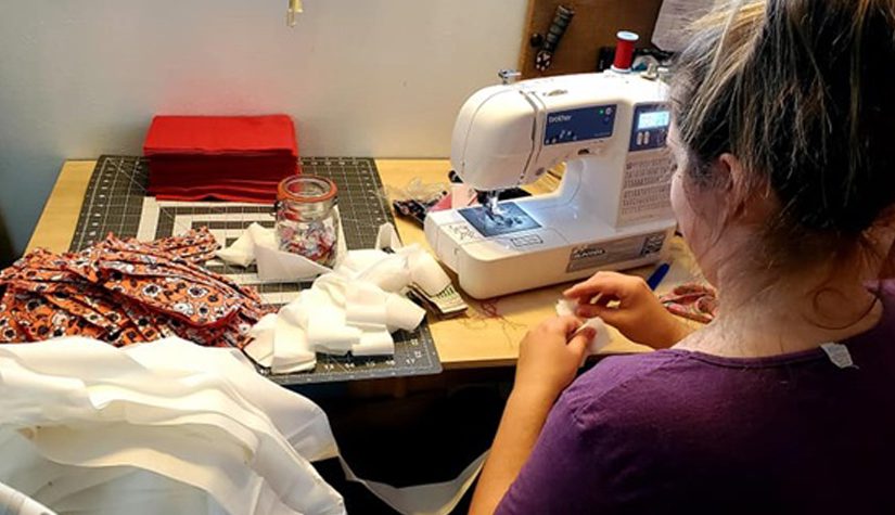 A woman uses a sewing machine to make masks.