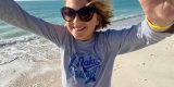 A young girl wearing sunglasses on the beach.