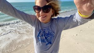 A young girl in sunglasses enjoying the beach.