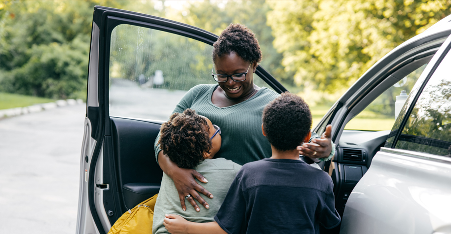 Kids hugging their mom before heading off to their first day of school.