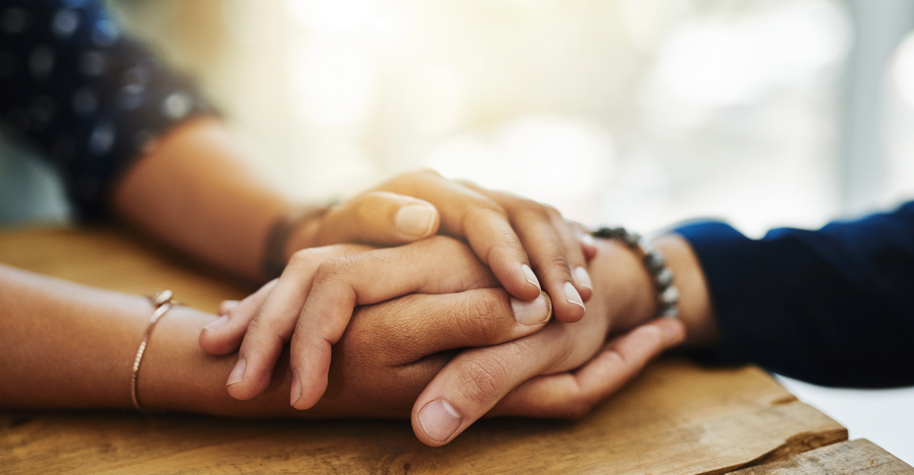 Two people holding hands across a table.