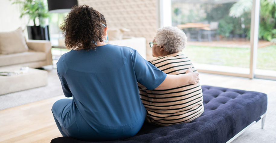 A caregiver talking to and consoling an older adult.