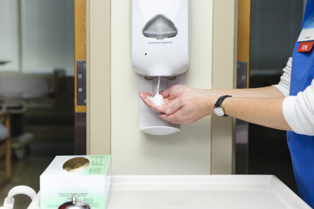 healthcare worker in a medical facility using touchless hand sanitizer