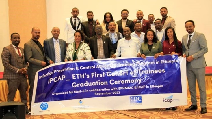 A group of people poses for a photo holding in front of them an IPCAP graduation banner.