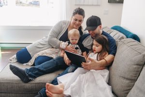 Millennial generation Family relaxing in living room. Father using a digital tablet with his son and his little austim girl