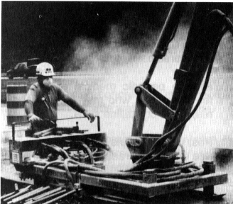 worker kicking up dust with a machine