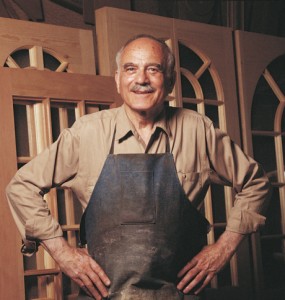 An older man standing in front of several unfinished doors