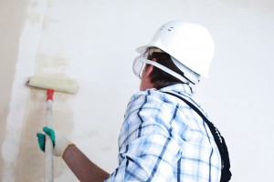 A worker rolls paint onto a wall