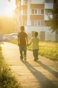 Two boys running together on street with sun back light, toned image