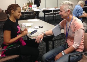 Photo of Dr. Teri Larkins measuring a coworker's blood pressure.