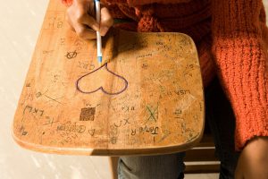 Student drawing a heart on her desk