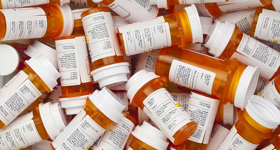 A jumble of orange prescription pill bottles with white labels and lids.