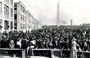 A crowd of people with the Washington Monument in the distance.