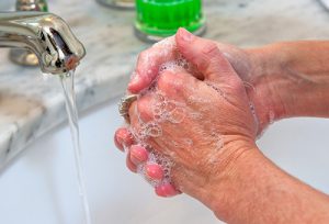 Photo of someone washing their hands in a sink.