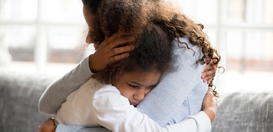 Mother and daughter embracing sitting on couch