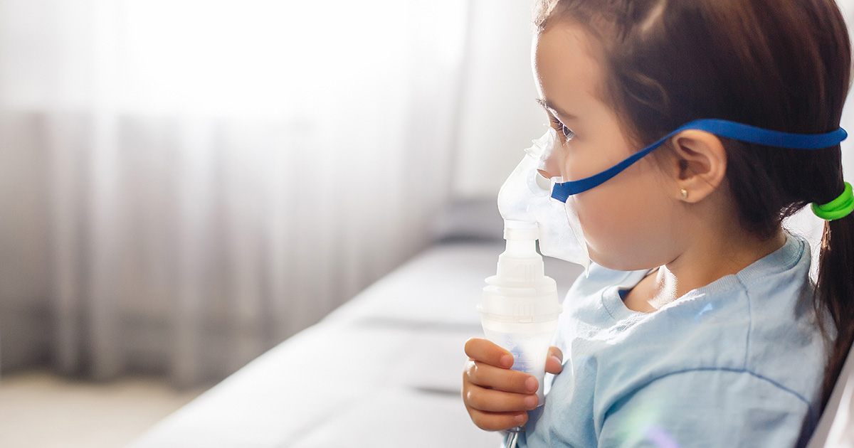 Little girl in a mask, treatments respiratory tract with a nebulizer at home