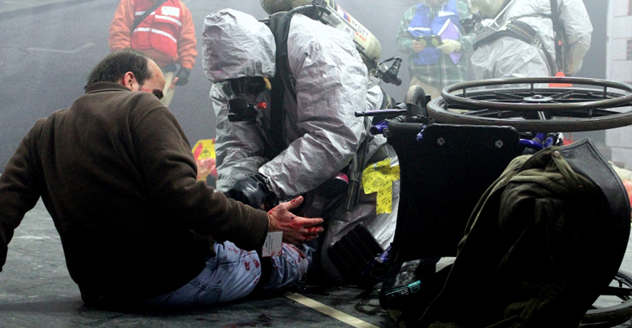 A first responder tends to a person with a simulated (or mock) injury during an emergency response exercise.