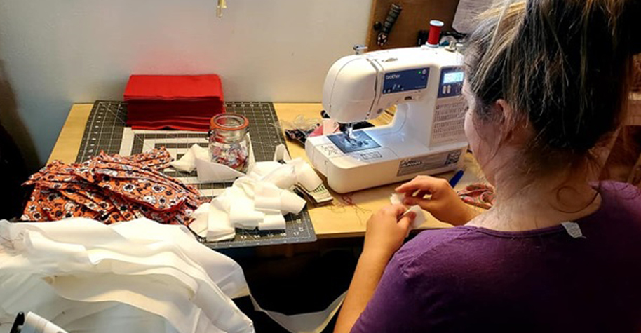 A woman uses a sewing machine to make masks.