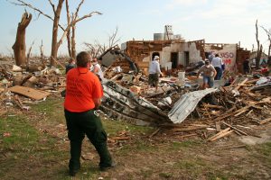 Photo of person in the foreground of residential tornado destruction